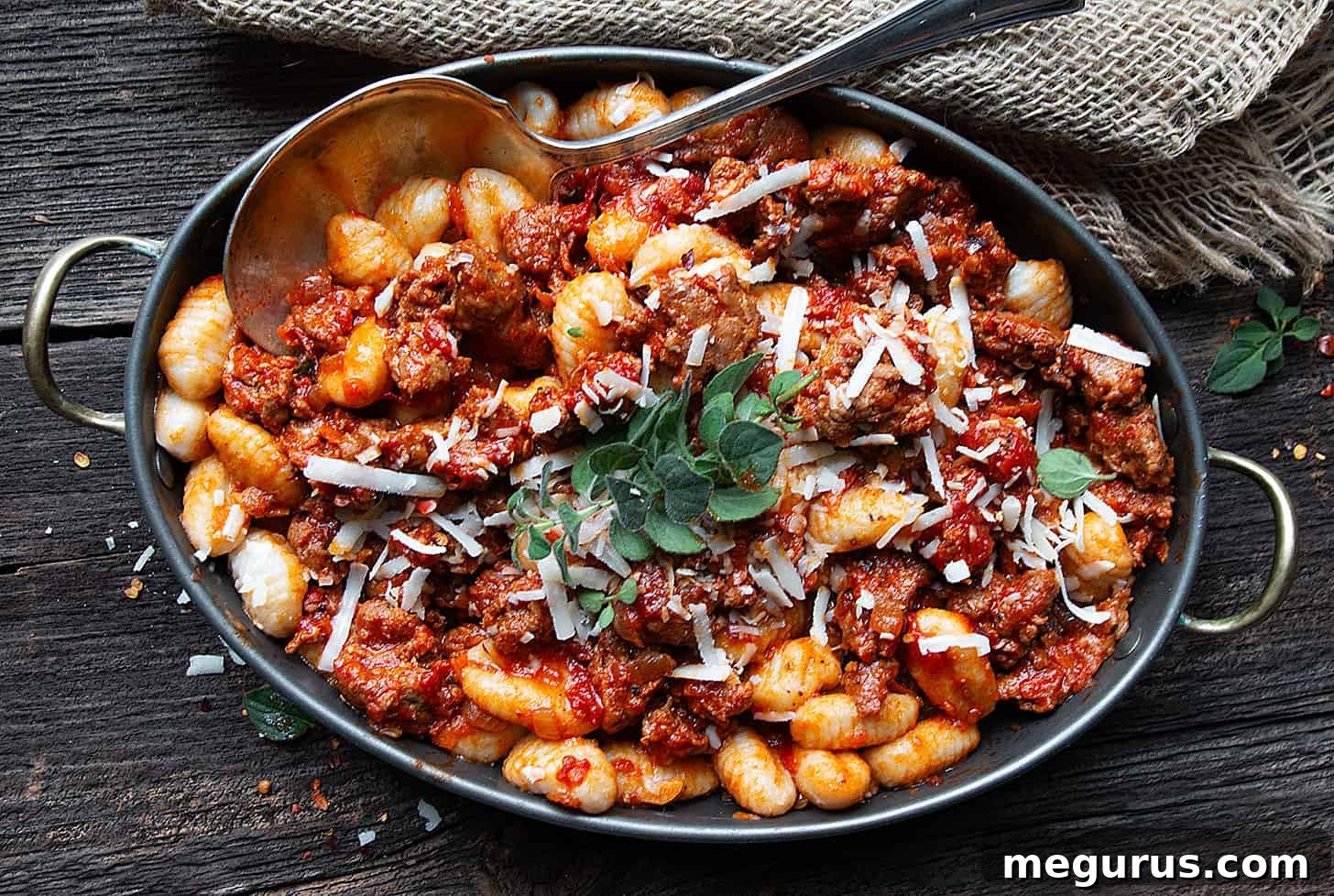 Gnocchi with Chorizo Sausage Sauce in a serving dish with a spoon, ready to be enjoyed.