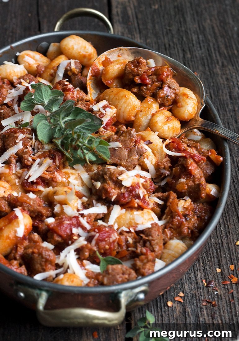 Close-up of Gnocchi with Chorizo Sauce in a serving bowl, garnished with fresh oregano.