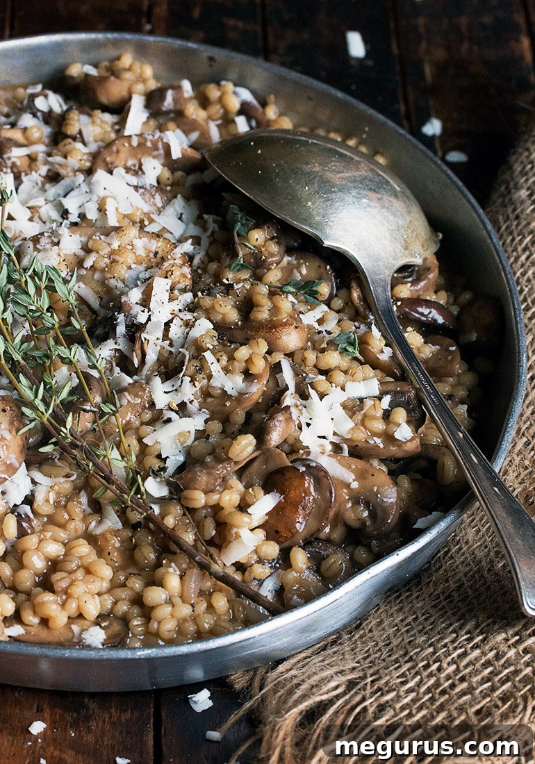 Mushroom Barley Risotto served in a bowl, garnished with fresh thyme and Parmesan