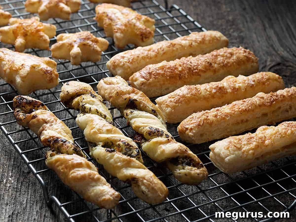 Golden puff pastry appetizers on a cooling rack, showcasing various shapes and toppings.