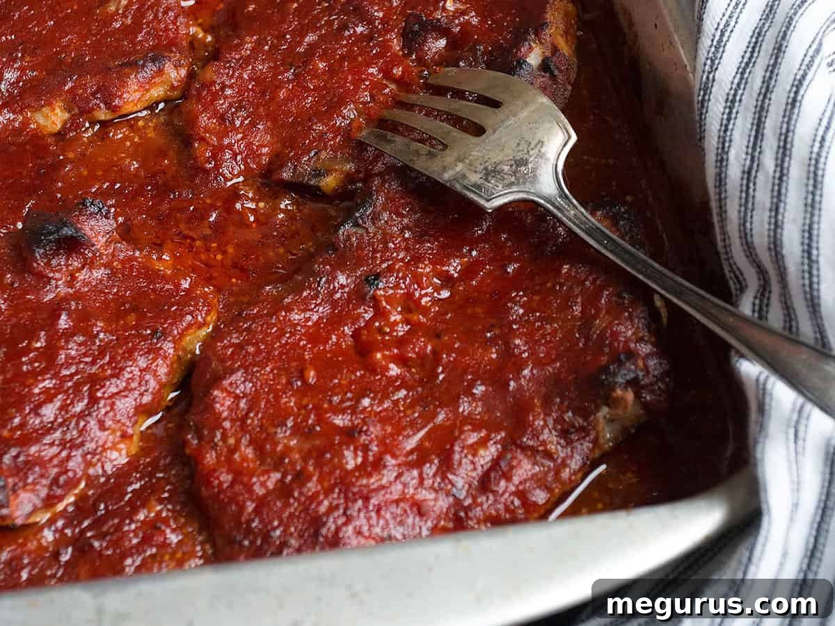 St. Louis style BBQ pork chops in baking pan, slow cooked to perfection with rich sauce