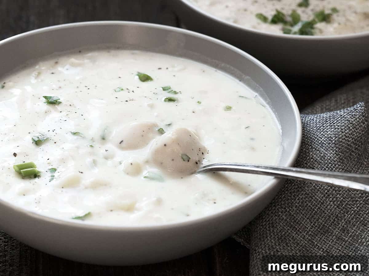 A bowl of thick and creamy seafood chowder with a spoon, garnished with fresh herbs