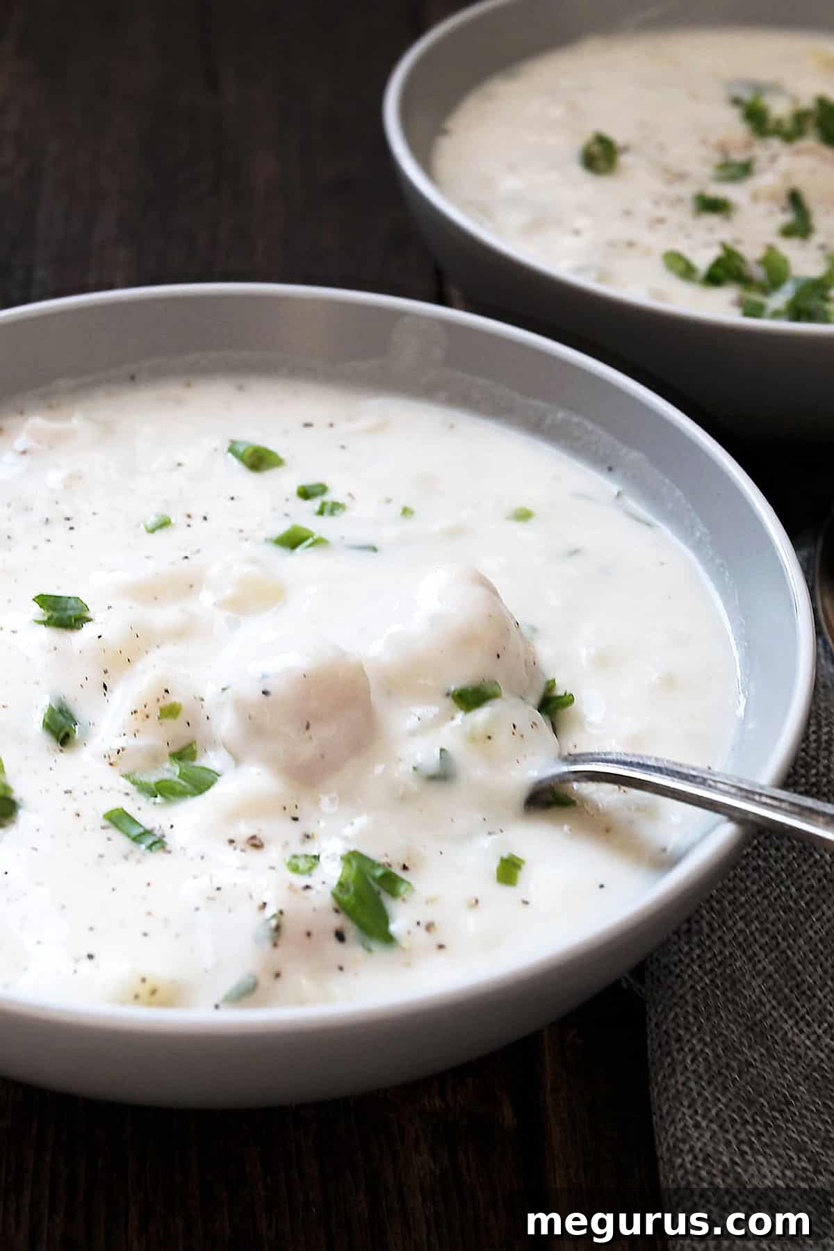 Close-up of a spoon scooping thick and creamy seafood chowder with visible seafood and potatoes