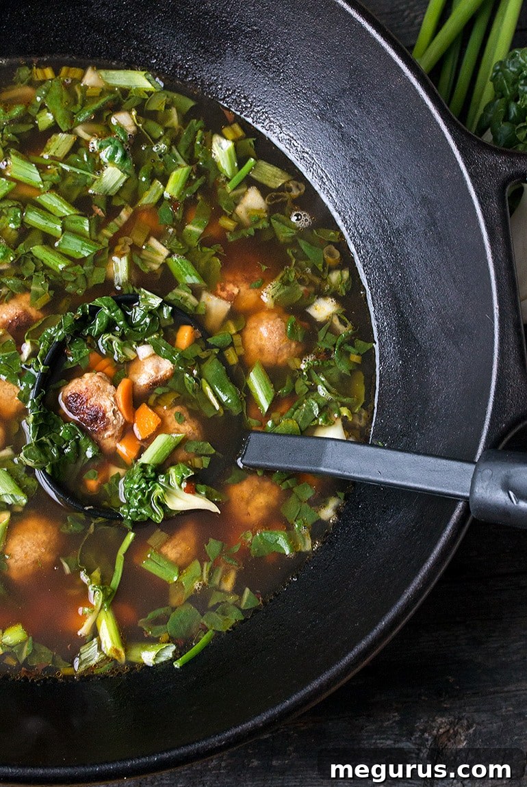 Close-up of Asian pork meatballs in a bowl of soup with bok choy