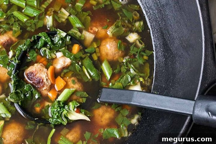Asian-inspired pork meatball soup with bok choy in cast iron wok