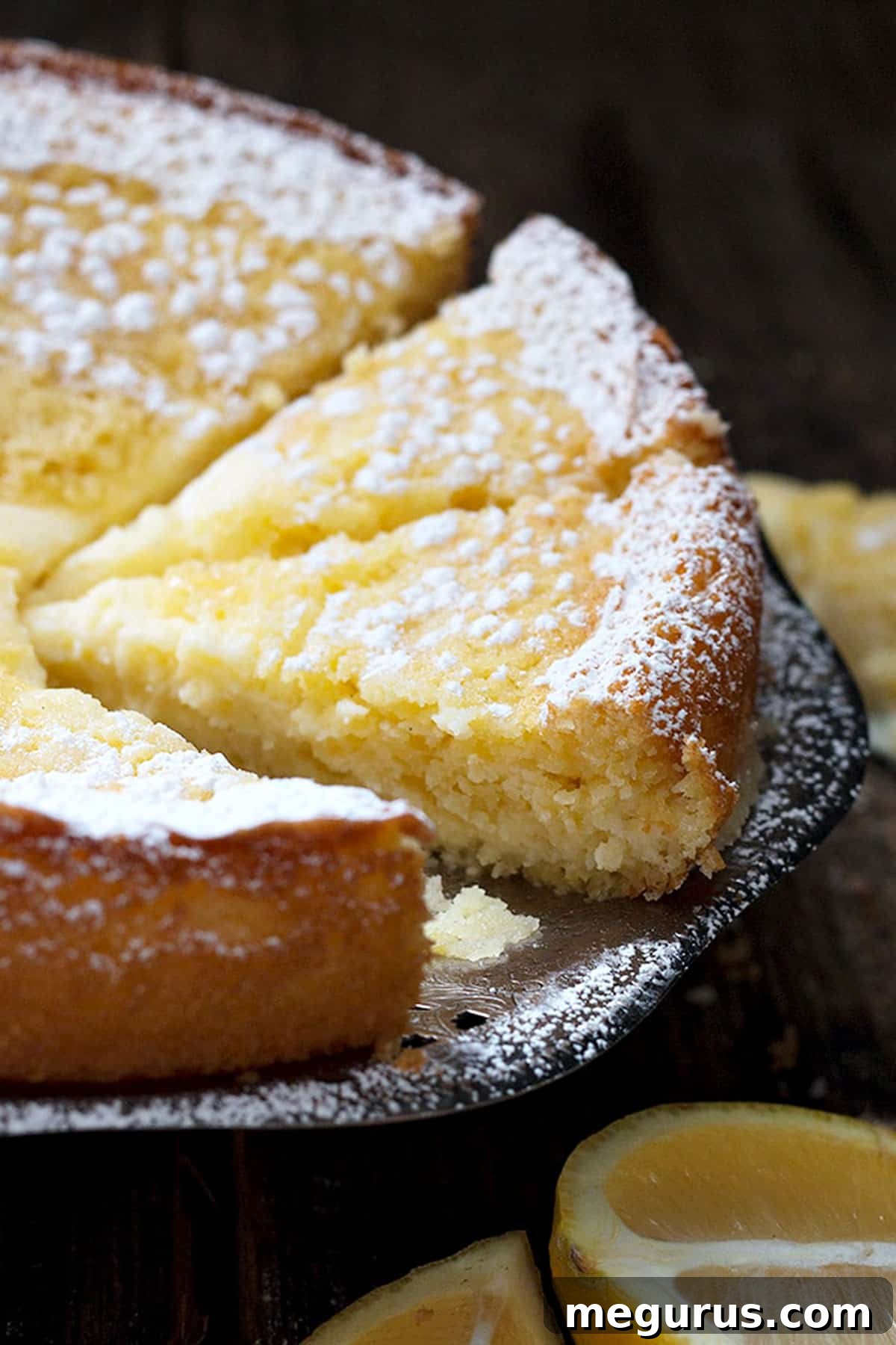 Another view of a whole Lemon Cream Butter Cake, subtly dusted with icing sugar