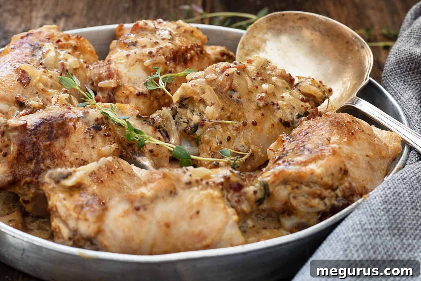 Golden-brown chicken dijon in a baking dish with a spoon, ready to serve.