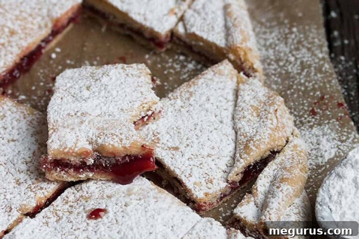 Freshly baked Raspberry Jam Squares, dusted with icing sugar and ready to be cut