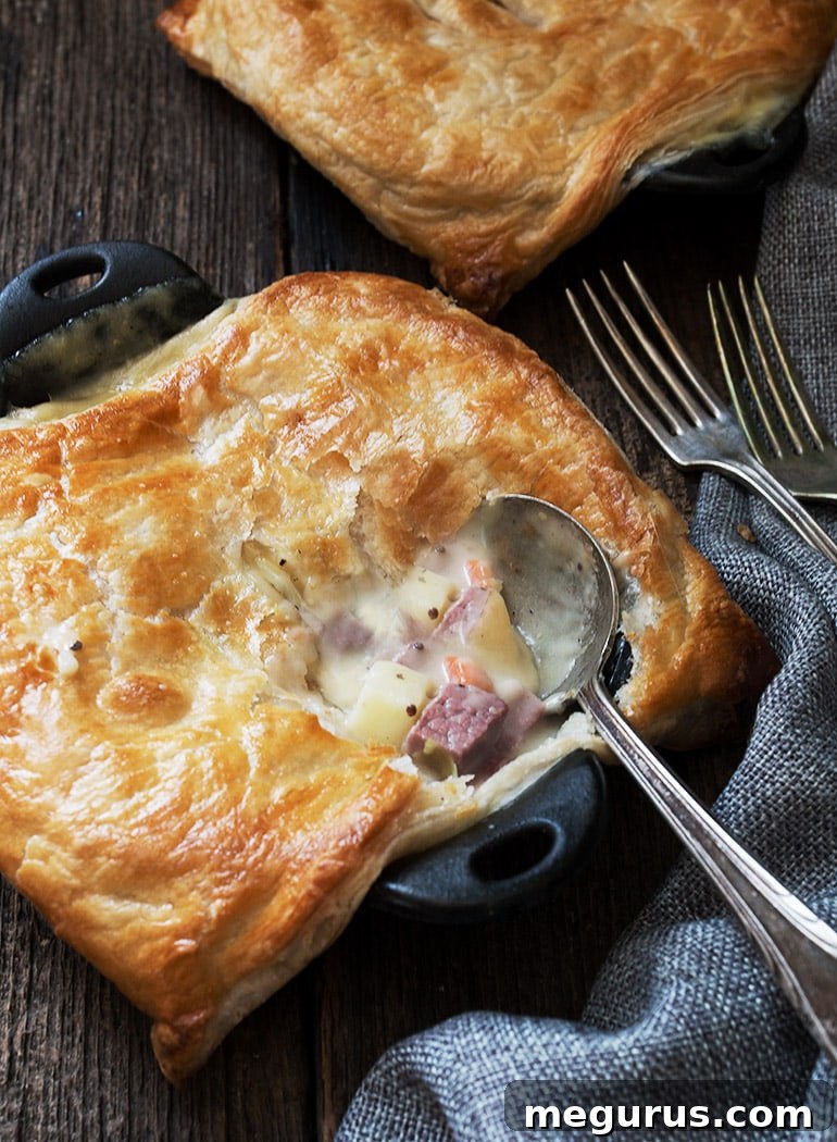 Close-up of a single corned beef and cabbage pot pie with a flaky puff pastry crust in a cast iron skillet