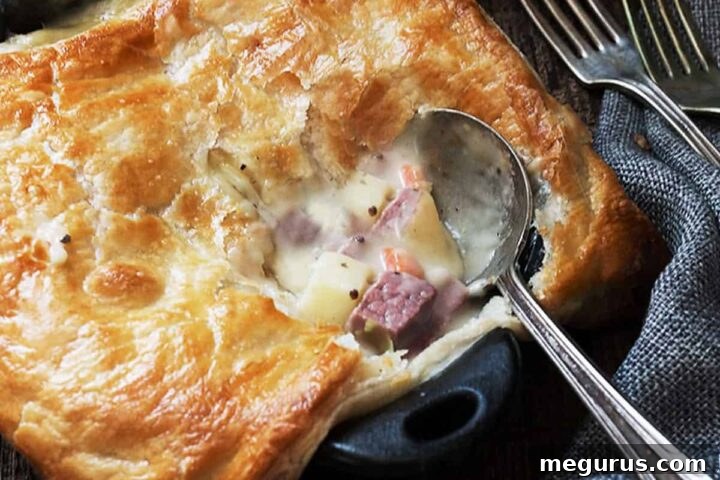 Cooked corned beef and cabbage pot pies in small cast iron skillets with a serving spoon