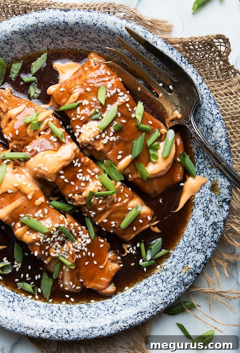 Close-up shot of Instant Pot Teriyaki Salmon with Sriracha Mayo and garnishes, showcasing its flaky texture and glossy sauce.