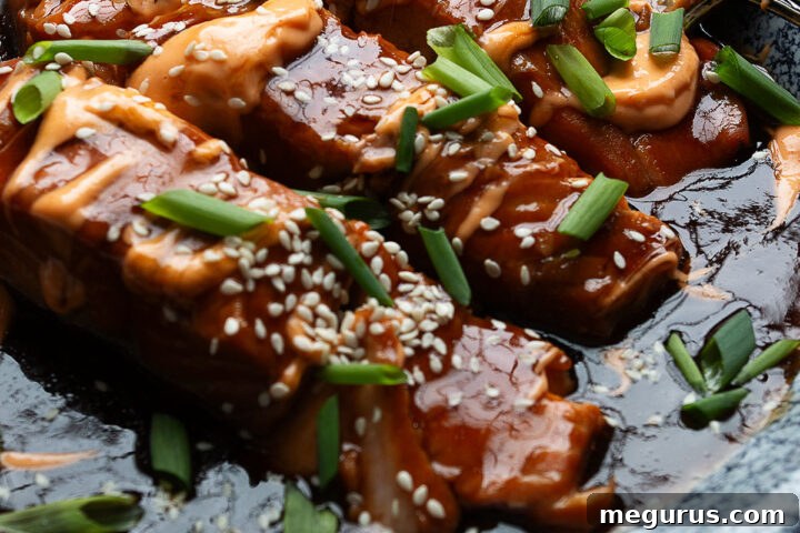 Instant Pot Teriyaki Salmon with Sriracha Mayo on a white plate, garnished with green onions and sesame seeds.