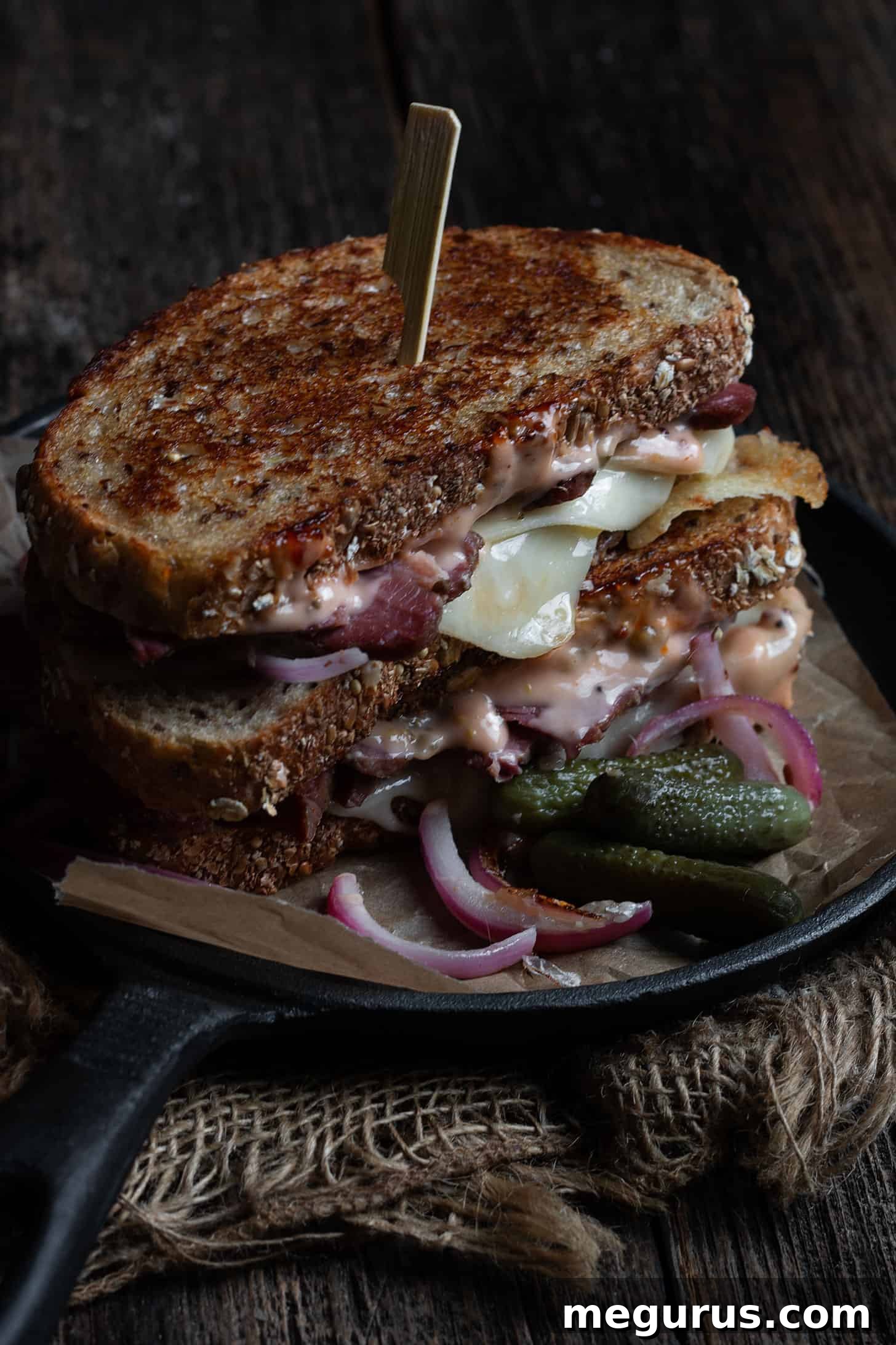 Grilled Reuben Sandwich served on a platter with dill pickles, ready to enjoy