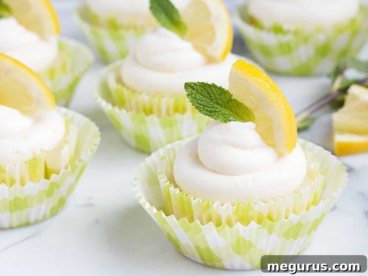 Beautifully frosted lemon cupcakes with a fresh lemon slice and mint sprig garnish