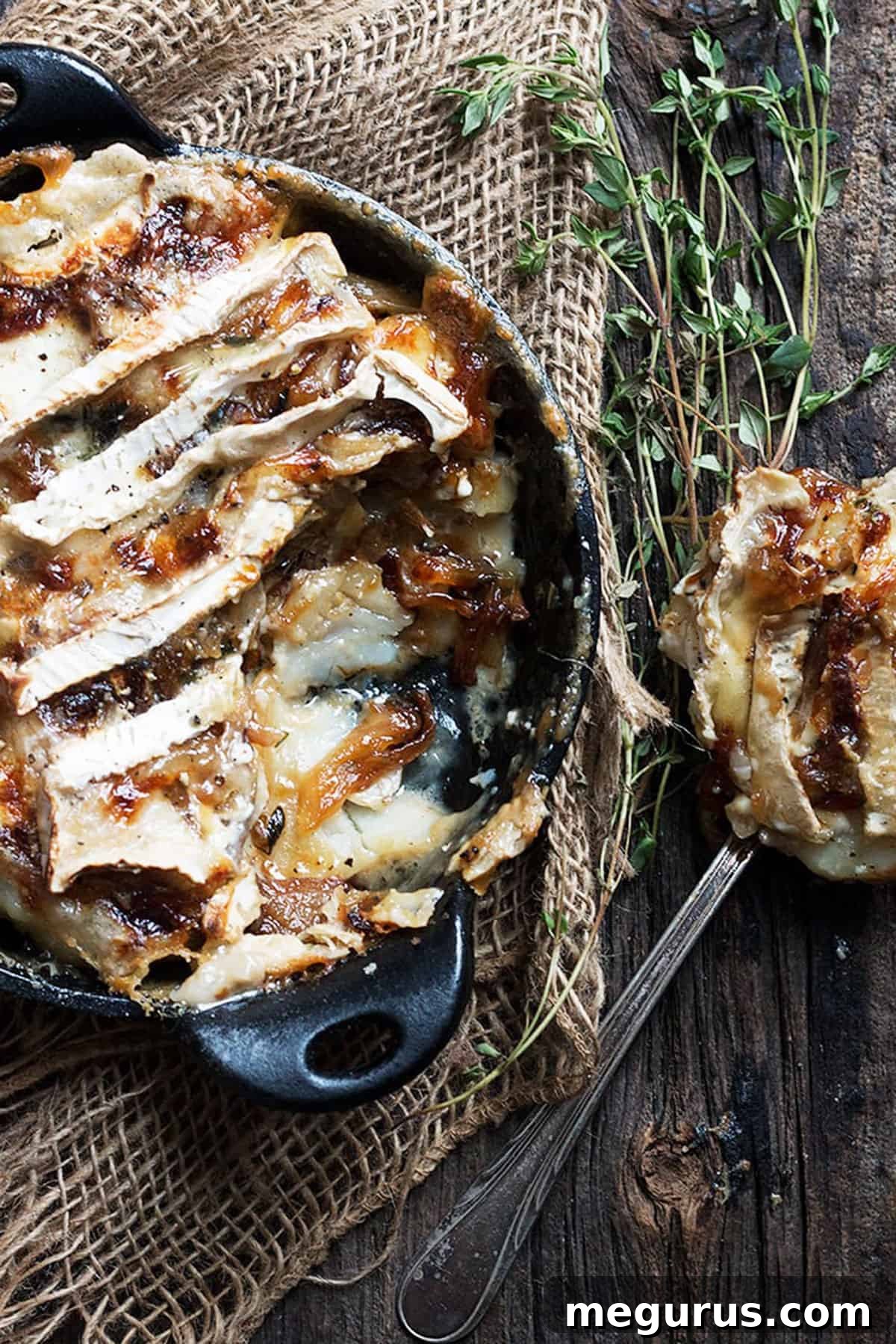 Close-up shot of a small cast iron skillet filled with Tartiflette, showing the melted Brie cheese and creamy potatoes.