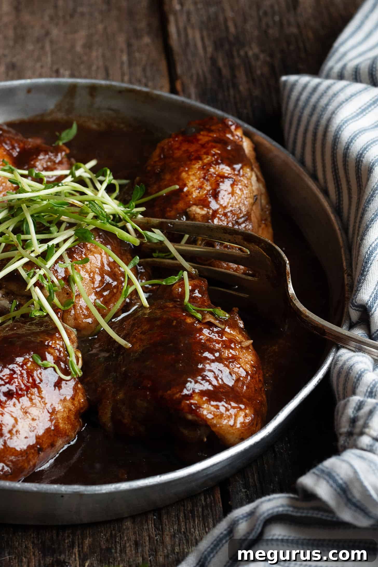 Balsamic chicken thighs in serving dish with fork.