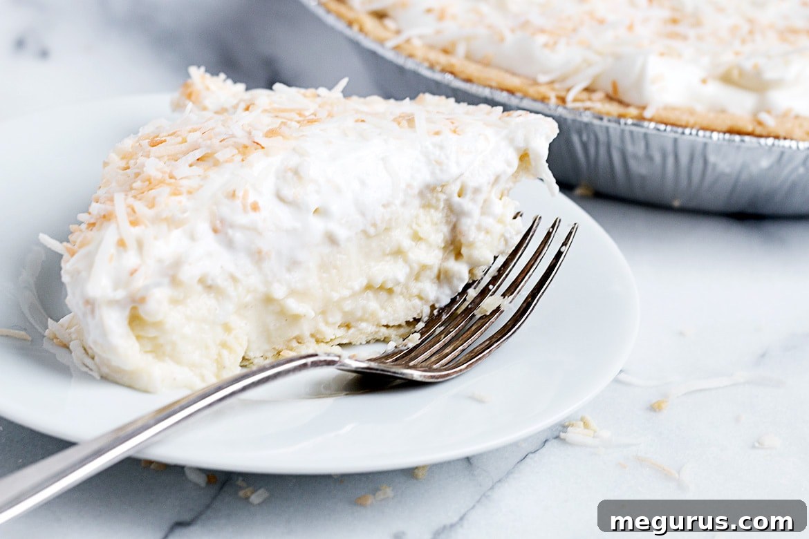 A slice of Simply Perfect Homemade Coconut Cream Pie on a plate, garnished with whipped cream and toasted coconut flakes, ready to be enjoyed.