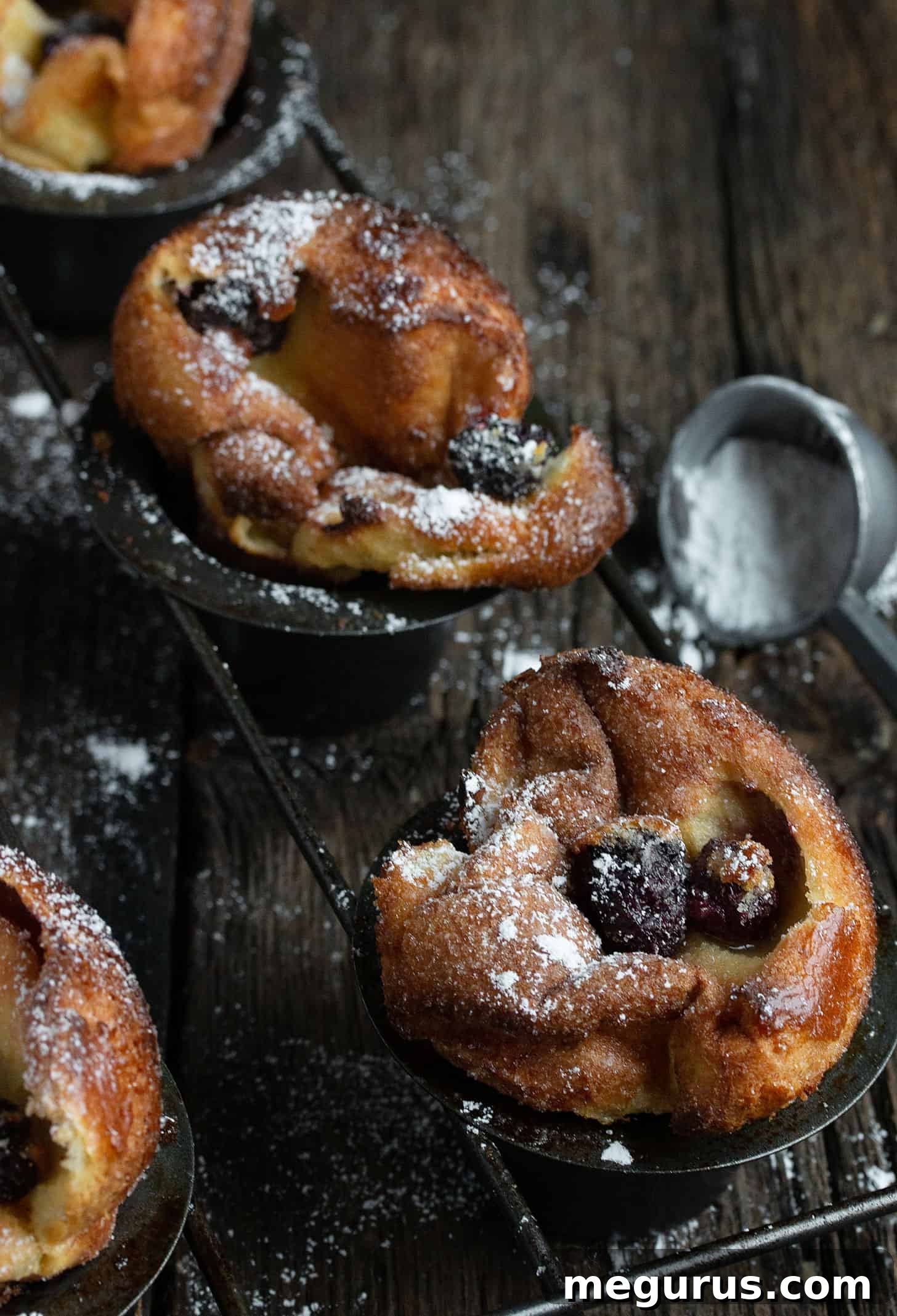 Close-up of a single sugar crusted blackberry popover, showing the delicate sugar coating and a peek of the juicy blackberry.