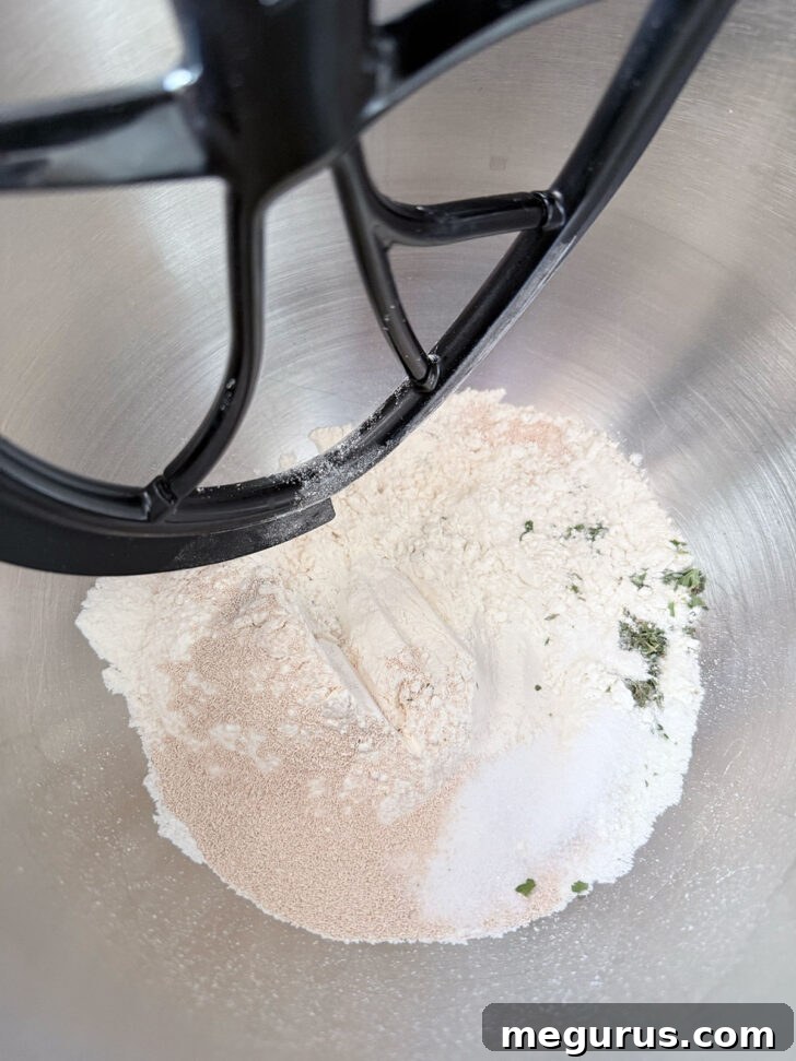 Dry ingredients for focaccia muffins in a mixer bowl with a paddle attachment.