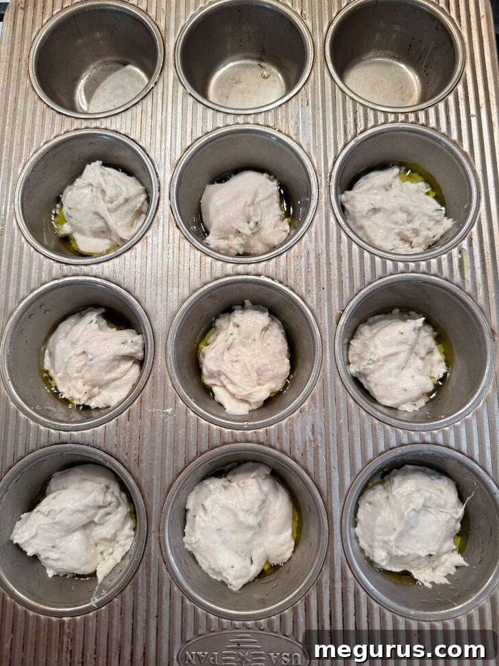 Focaccia dough divided evenly between 9 muffin cups.
