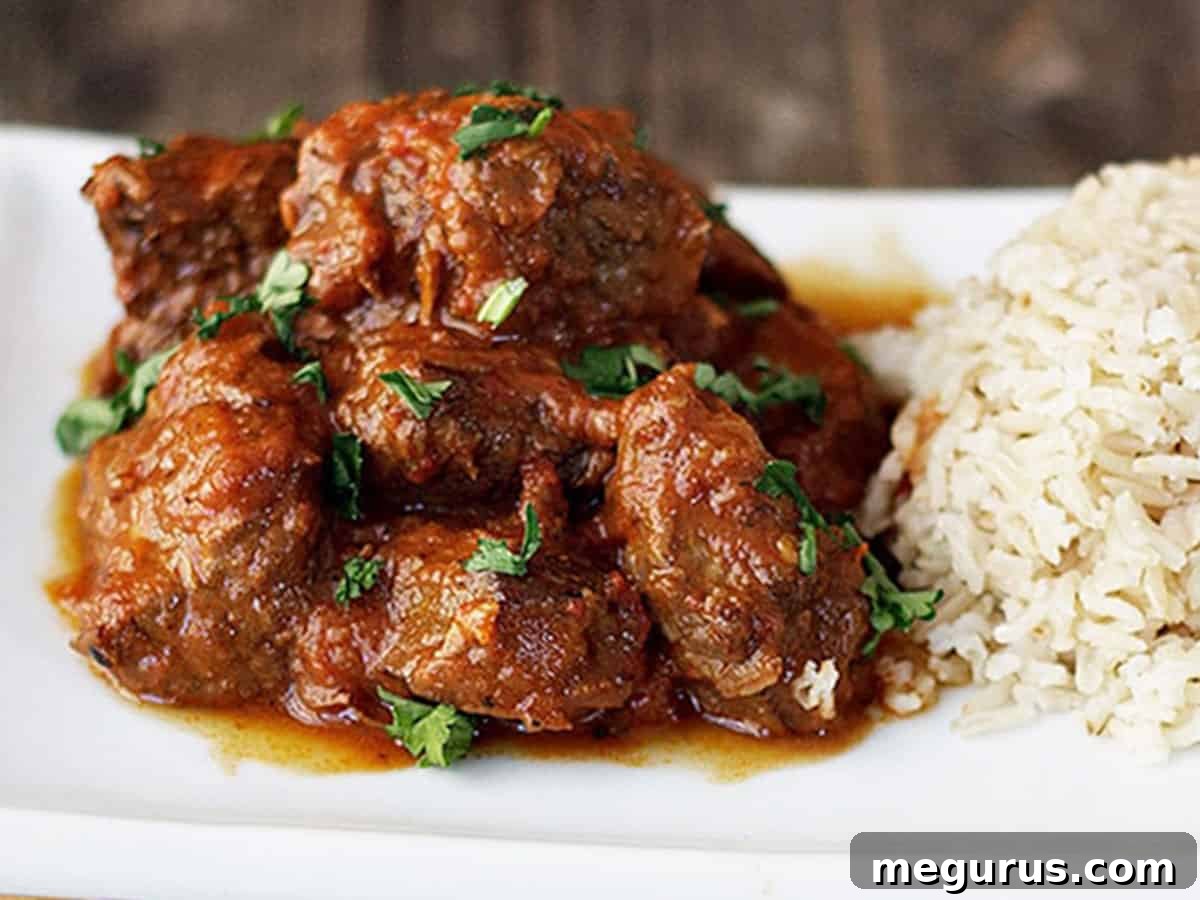 Aromatic spiced beef curry served on a plate with fluffy Basmati rice, garnished with fresh cilantro.