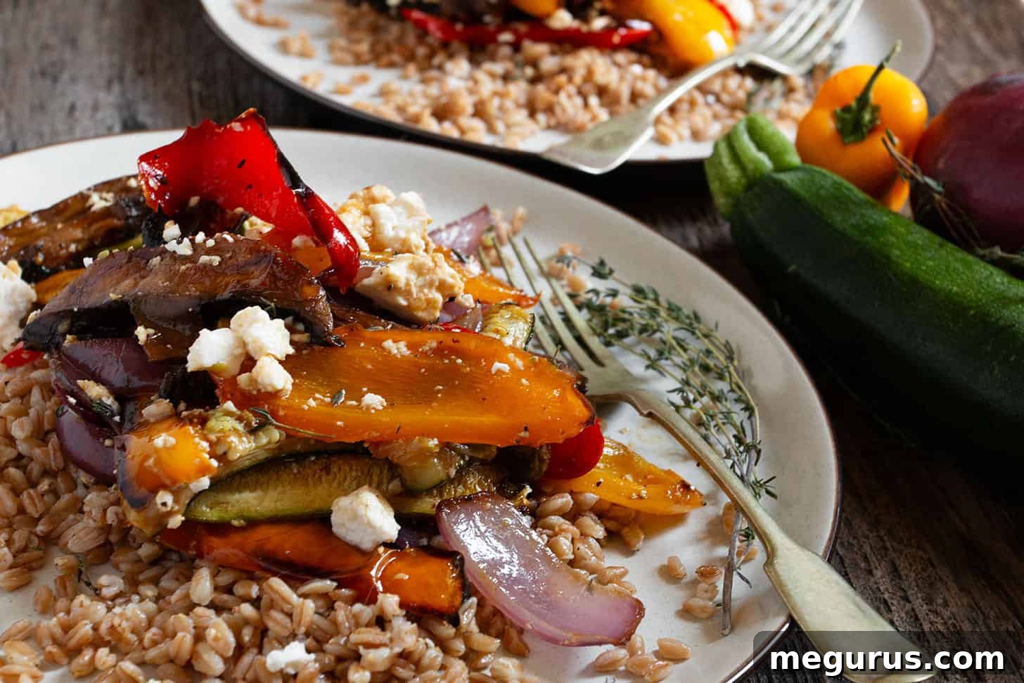 A beautifully plated roasted vegetable farro salad with a fork, showcasing vibrant colors and textures.
