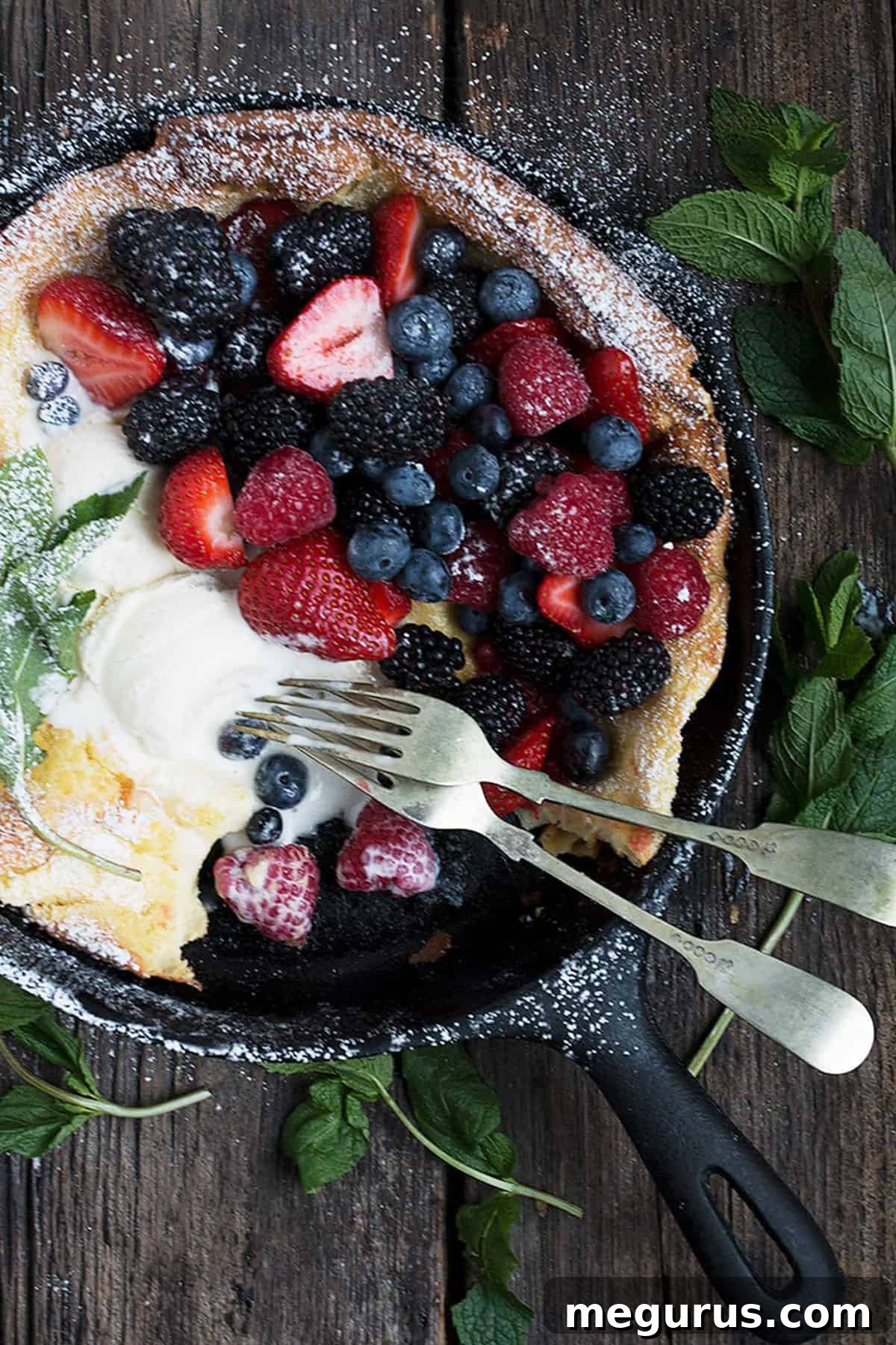 Close-up of a fresh fruit Dutch Baby pancake overflowing with berries in a cast iron skillet