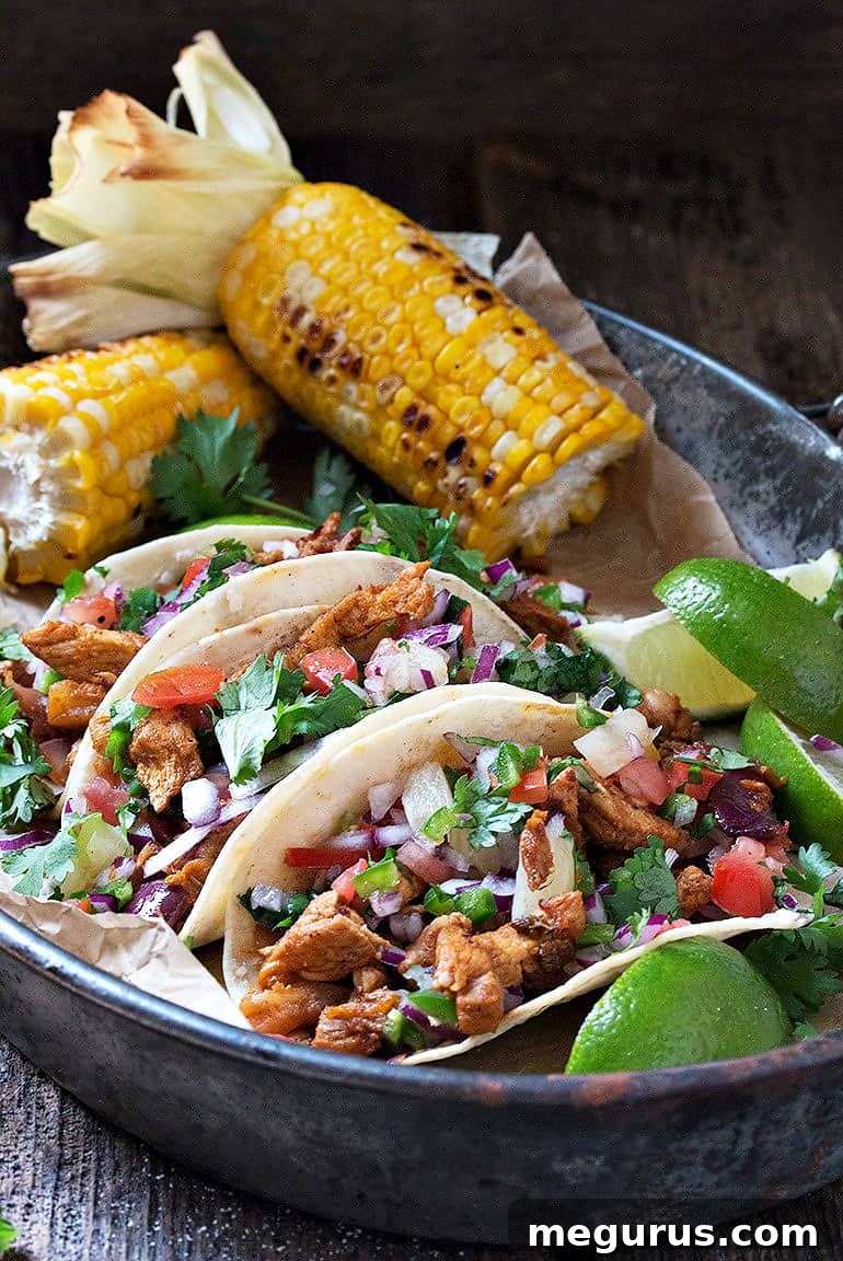 Close-up of freshly made Al Pastor tacos, garnished with cilantro and lime, on a rustic serving board.