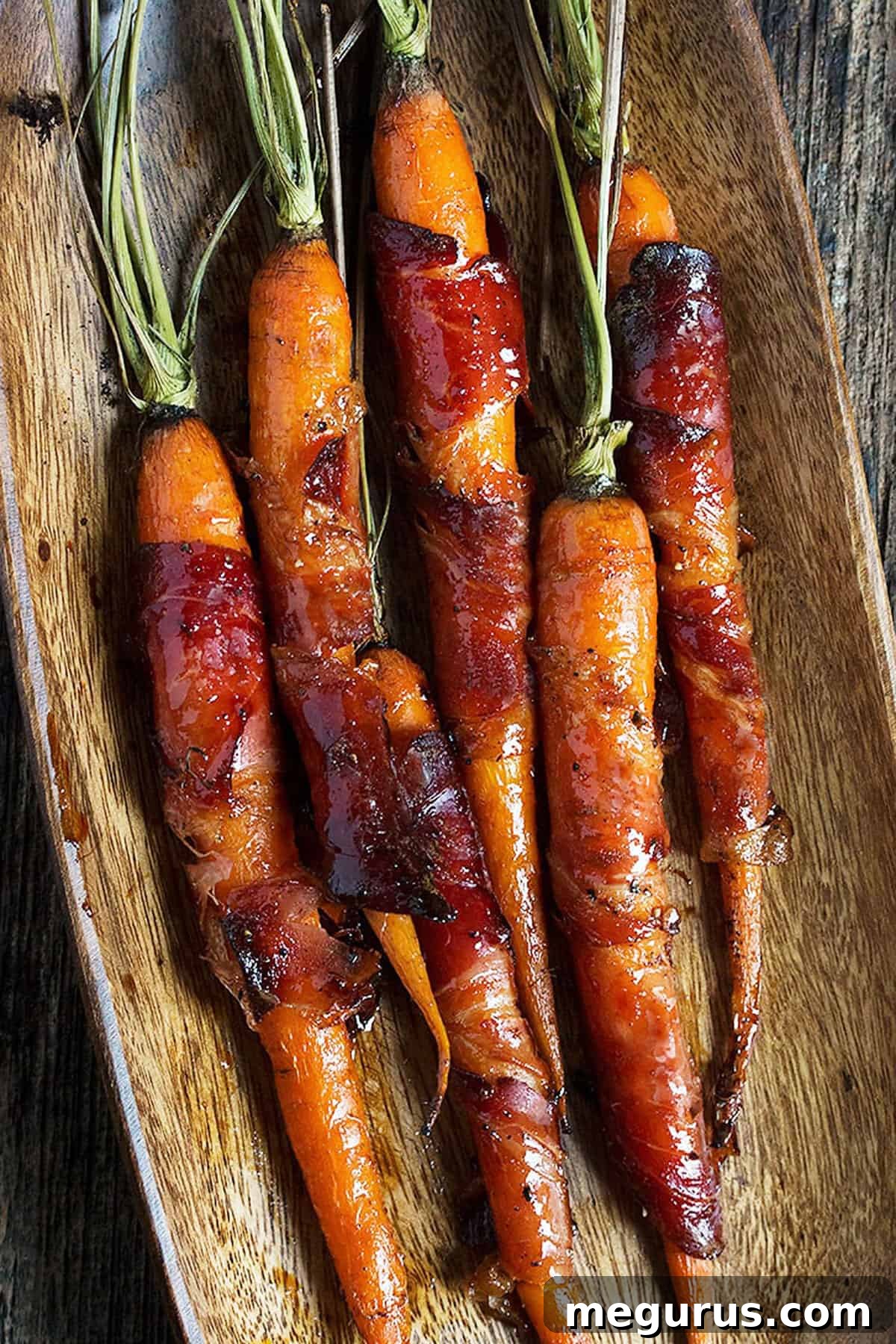 Close-up of maple glazed bacon wrapped carrots with crispy bacon and tender carrots.