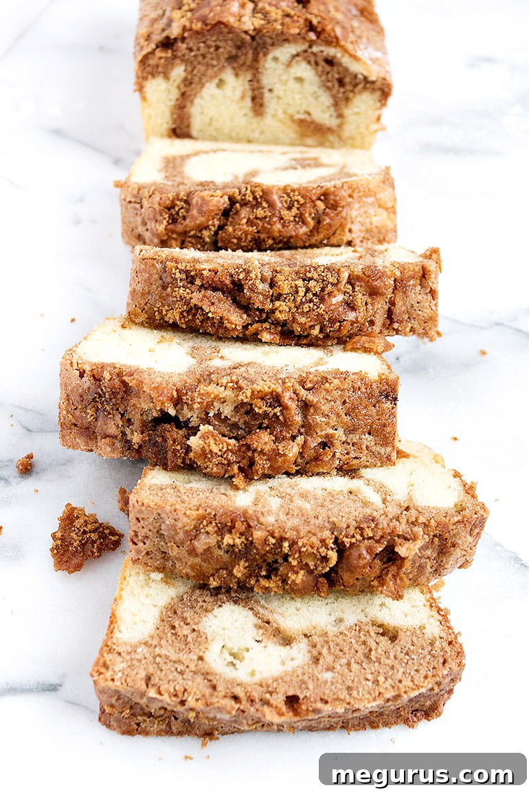 Close-up of a generously sized slice of cinnamon swirl pound cake loaf, showcasing the distinct cinnamon layer and golden streusel topping.