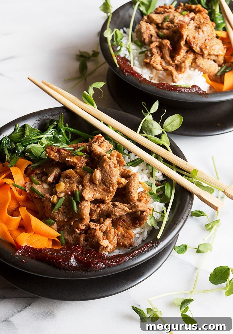 Close-up of a serving of spicy pork rice bowl, showing the texture of the pork and the fresh vegetables