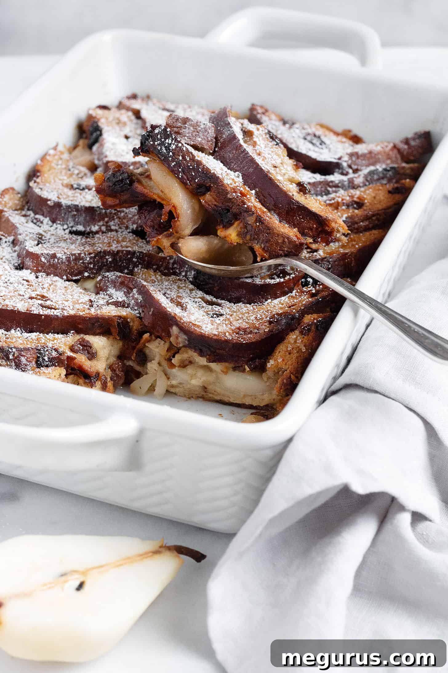 Close-up of golden brown Gruyere and pear bread pudding in a baking dish, freshly baked and ready to serve.