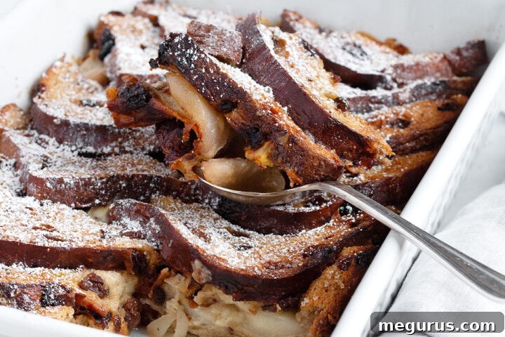Gruyere and pear bread pudding in baking dish with spoon.