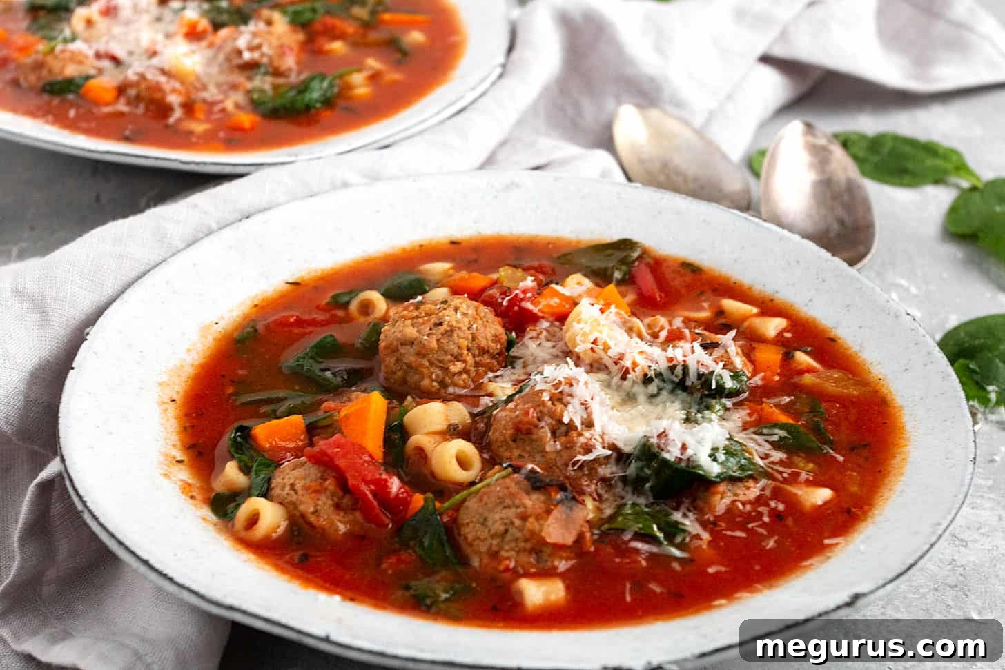 A steaming bowl of hearty Italian Meatball Soup, garnished with fresh parsley and Parmesan cheese, ready to be served for a comforting dinner.