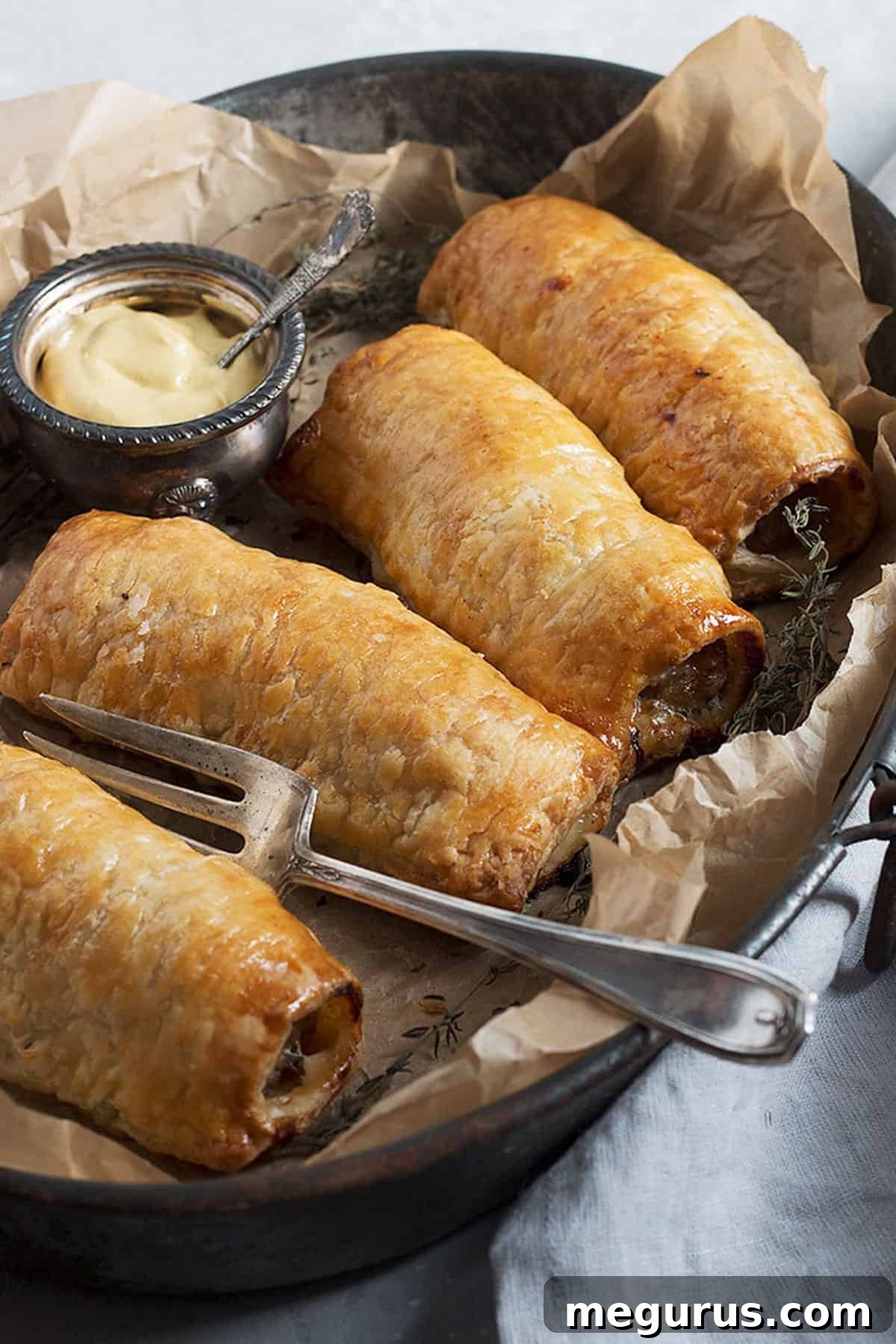 Assorted homemade sausage rolls presented on a platter with various mustards and a fresh green salad.