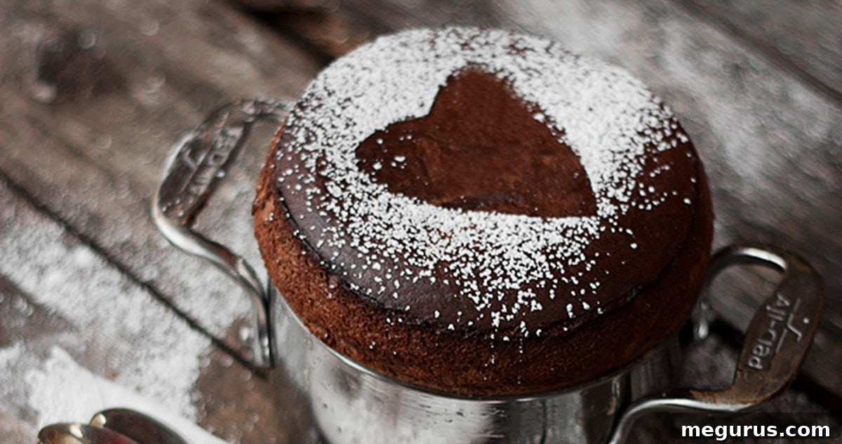Airy chocolate soufflé dusted with powdered sugar, forming a heart shape on top, served in a ramekin.