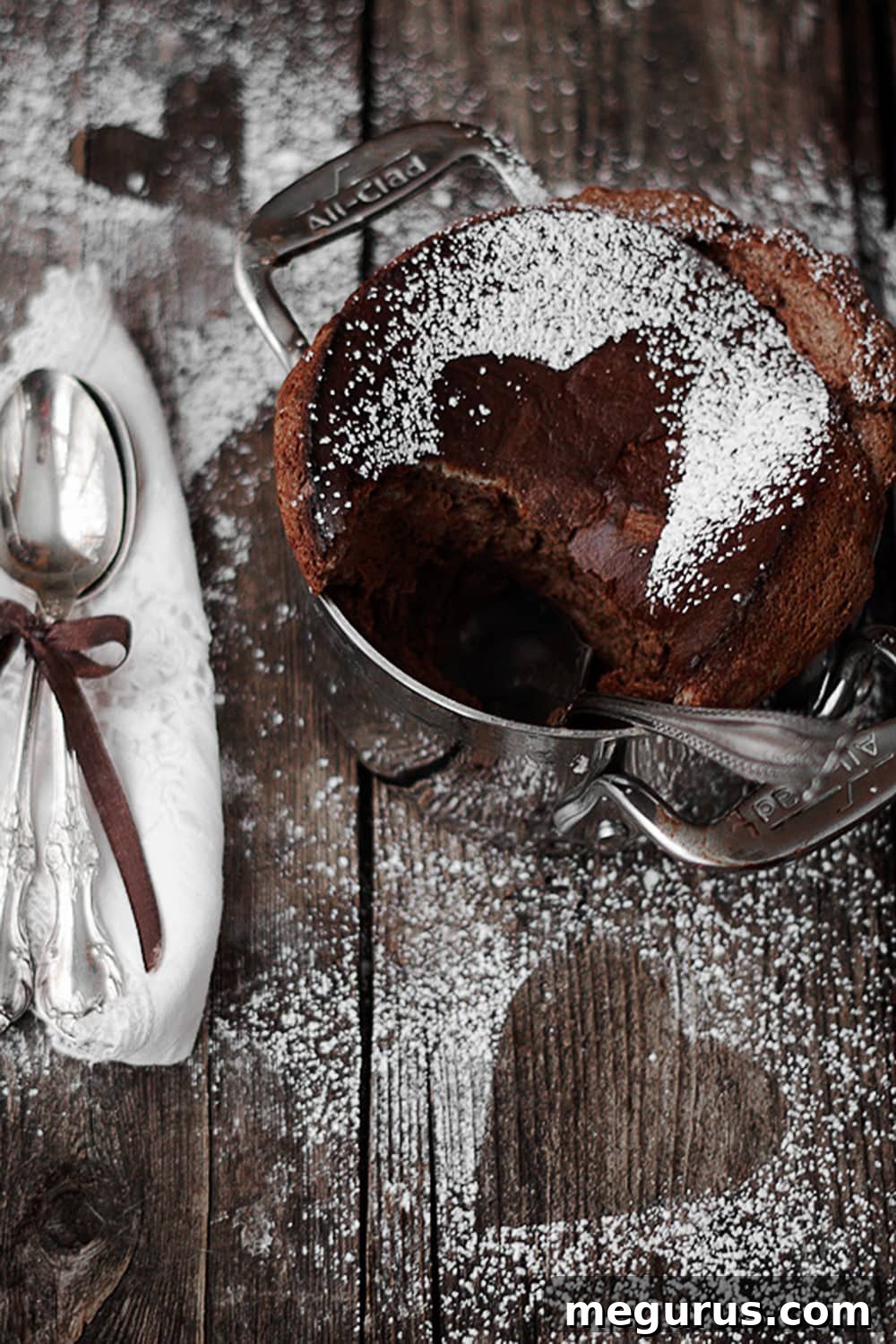 Rich chocolate soufflé, a spoonful removed revealing its airy, molten interior, served in a ceramic dish.