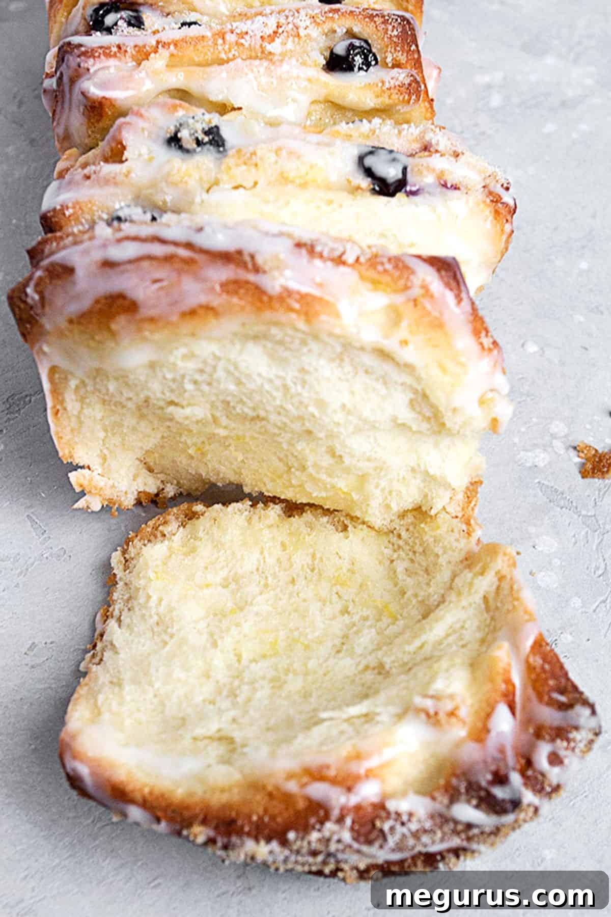 Close-up of a slice of Lemon Blueberry Pull Apart Bread pulled from the loaf, showing layers of dough, blueberries, and lemon sugar