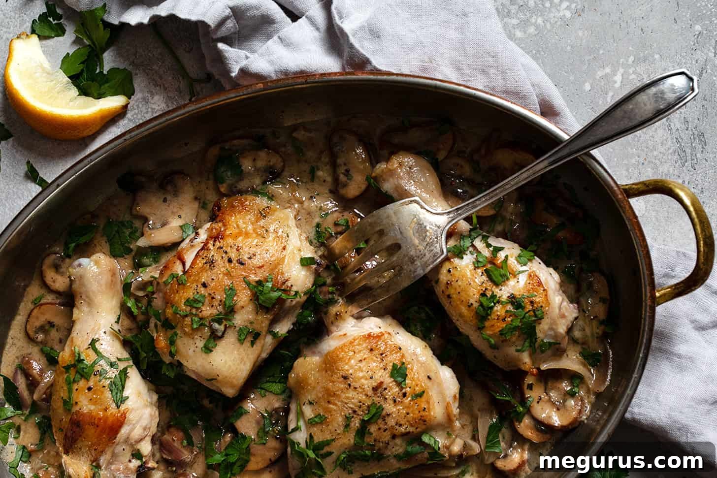 Golden-brown chicken riesling in a pan with a fork, showing crispy skin and creamy sauce