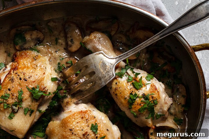 Chicken Riesling in a pan with a fork, showing the creamy sauce and mushrooms.