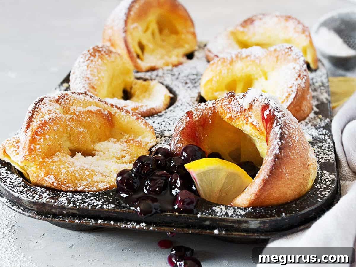 mini Dutch babies in muffin tin with lemons and blueberry sauce