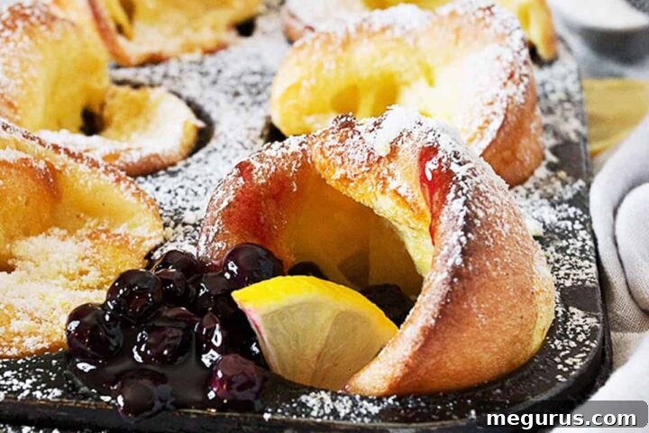 mini Dutch babies in muffin tin with lemons and blueberry sauce
