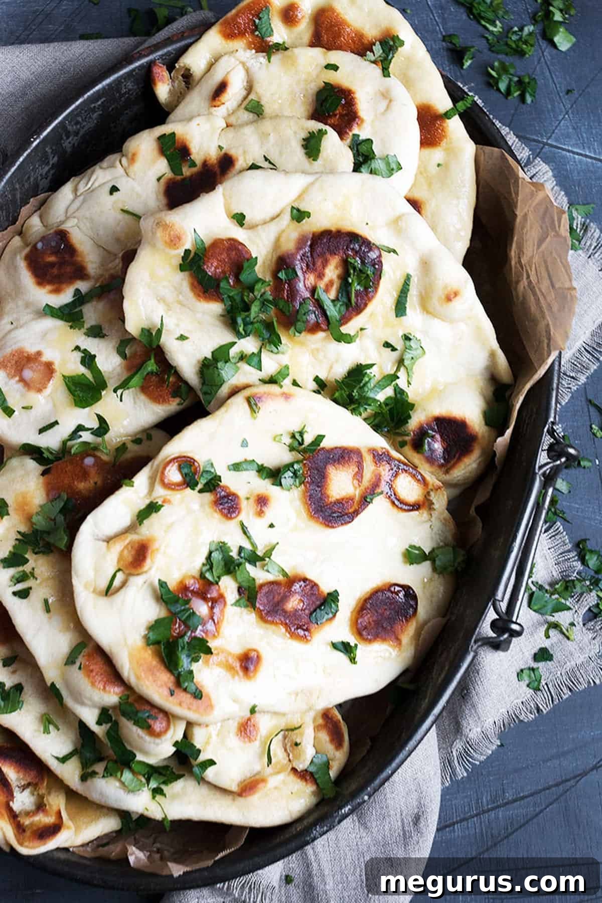 Close-up of fluffy garlic naan bread, fresh from the pan, on a metal platter.