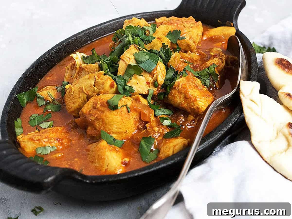 Flavorful Easy Chicken Vindaloo in a cast iron dish, garnished with fresh cilantro, ready to be served