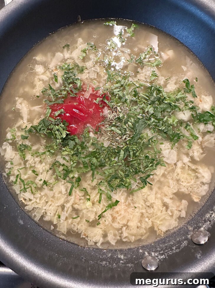 A mix of chicken broth, Worcestershire, ketchup, parsley, and thyme being stirred into the skillet with softened onions.