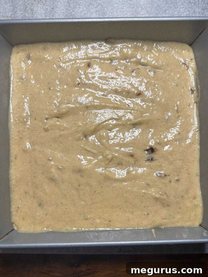 Smooth cake batter spread evenly in a greased baking pan, ready for the oven