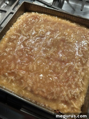 The warm, bubbling coconut topping is spread over the freshly baked date cake