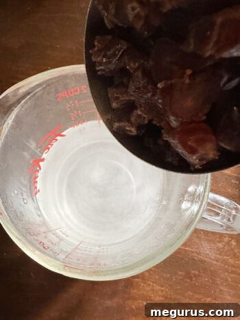 Chopped dates are added to a bowl with boiling water and baking soda to soften