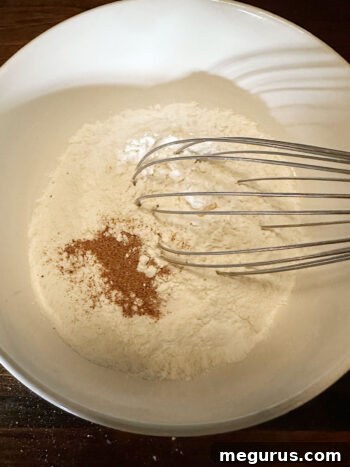 Dry ingredients, including flour, baking powder, nutmeg, and salt, are whisked in a bowl