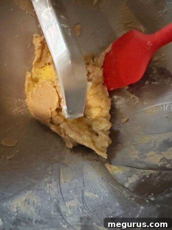 The sides of the mixing bowl are scraped down to ensure all ingredients are combined